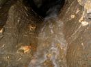 Brunneckerhöhle - Kleiner Wasserfall vor in grauem Material eingebackenem weißen Material.